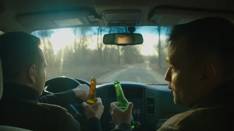 Scene of two men ride in a car with bottles of alcohol, they drink alcohol while Stock Footage 121625827