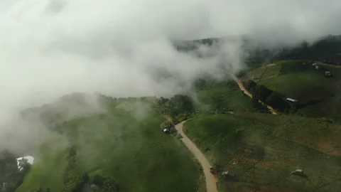 Scenery farmland on hill with rustic path for transport. Fly through clouds Stock Footage 202220076