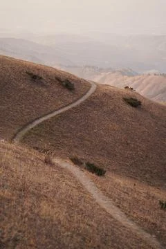 Scenery mountain trail going through hills at sunset. Stock Photos