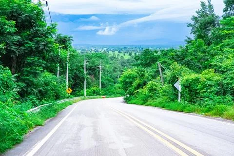 Scenery of the road going down the mountain with beautiful green trees on bot Stock Photos