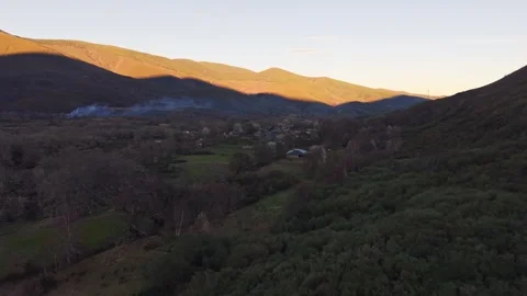 Scenic aerial flight over mountain valley village at sunset in Candin Stock Footage 340532999