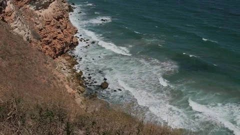 Scenic aerial view of ocean waves breaking on a rocky cliff shore Stock-Footage 342649772