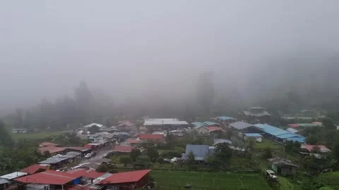 Scenic aerial view of a small mountain village covered in thick fog Stock Footage 344980252