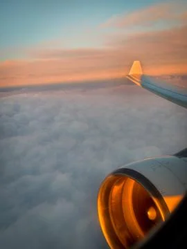 Scenic airplane view with glowing sunset over clouds Stock Photos