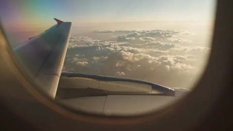 Scenic Airplane Window View of Wing Floating Above Clouds Illuminated by Sunset Stock Footage 345275307