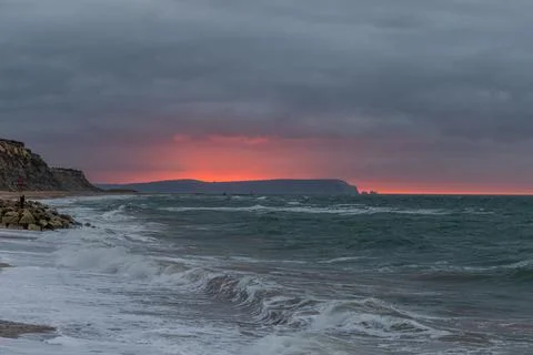 A scenic and dramatic sunset over a choppy sea with dark black thundery sky Stock Photos