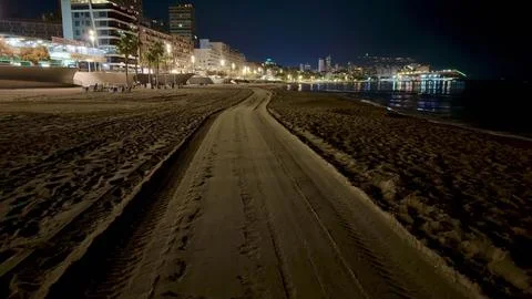 Scenic Beach Pathway at Night Featuring Beautiful City Lights Illuminating .. Stock-Fotos