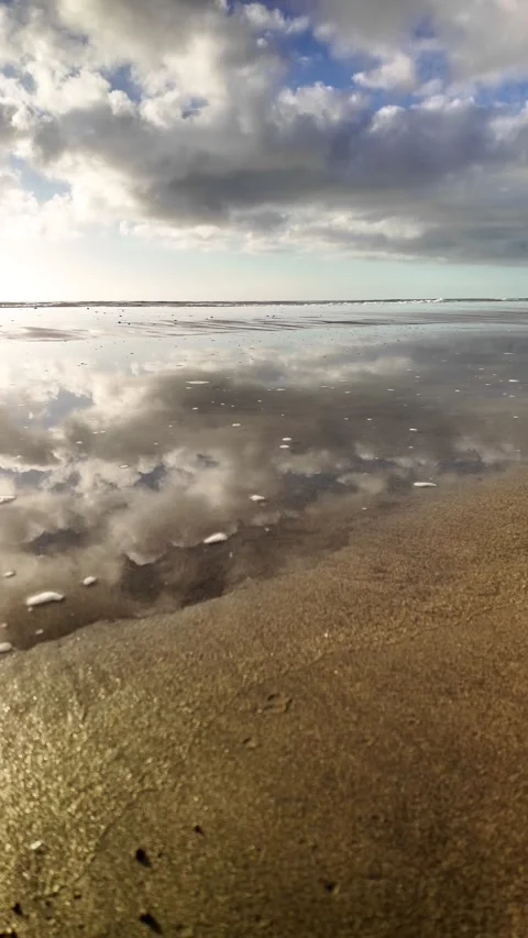 Scenic beach view with clouds reflecting in the wet sand Stock Footage 346177797