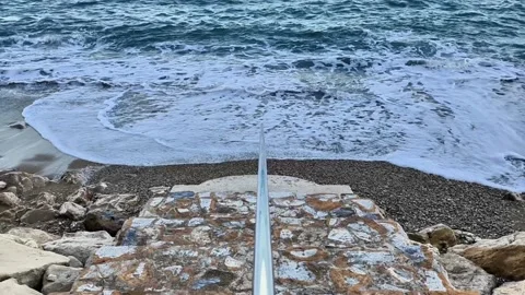 The scenic beach view features calm waves gently touching a rocky shore Stock Footage 316782469