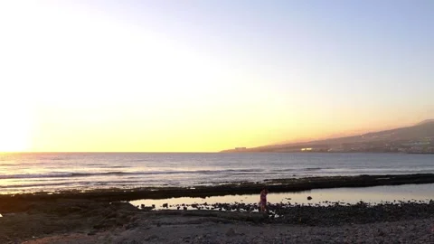 Scenic beach view with a setting sun, illuminating Tenerife's landscape in .. Stock Footage 280824089