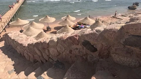 Scenic Beach View with Stone Steps Leading to Shoreline and Beach Umbrellas 库存影片 330098990