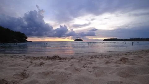 Scenic beach view at sunset with clouds and distant islands Stock Photos