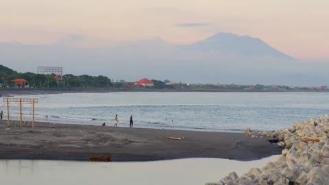 Scenic Beach with Volcano Backdrop, Locals Enjoying Sunset Activities in Bali 库存影片 300165266