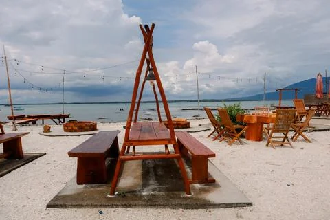 Scenic Beachfront Dining Area with Rustic Wooden Tables and Seating at Sunset Stock Photos