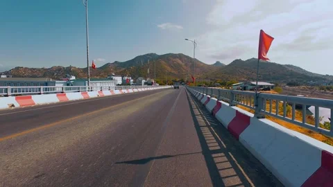 Scenic Bridge Road Driving Towards Rocky Mountains under Blue Sky Stock Footage 337028100