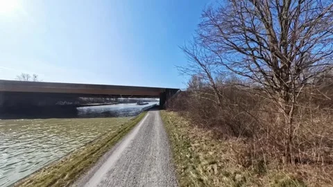 A scenic canal path beneath a grand bridge and a blue sky is perfect for Stock Footage 304872172