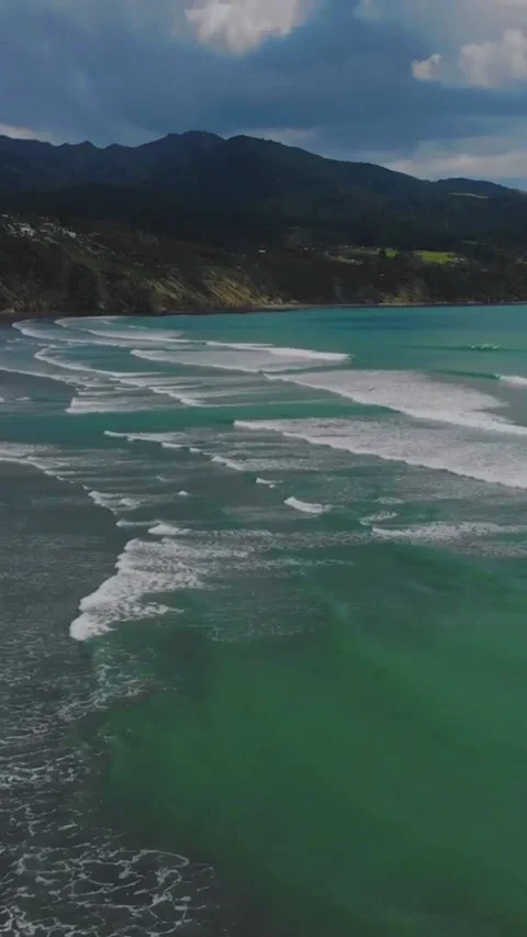 Scenic Coastal Beach with Rolling Waves and Mountain Backdrop Stock Footage 342315582