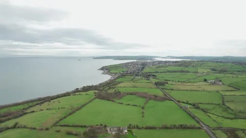 Scenic coastal view of green fields and distant harbor in early morning Stock Footage 310240797