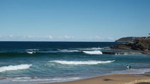 Scenic coastal waves breaking on an sandy beach under clear blue sky Stock Footage 317795405