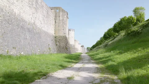 Scenic dirt path winding through a grassy moat next to a massive medieval stone  Stock Footage 336133513