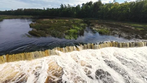 A scenic drone shot capturing the cascading waters of Kuldiga Waterfall flowing 스톡 동영상 282691345