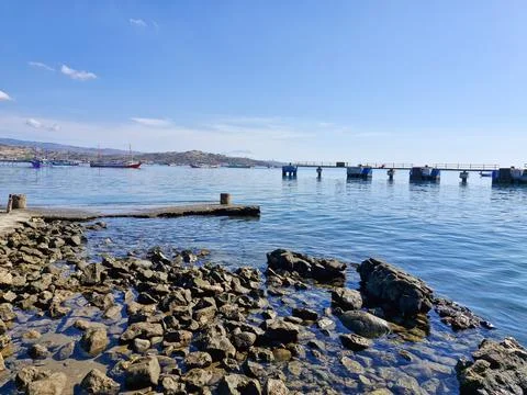 Scenic harbor view with a distant dock, fishing boats, and rocky shores whe.. Stock Photos