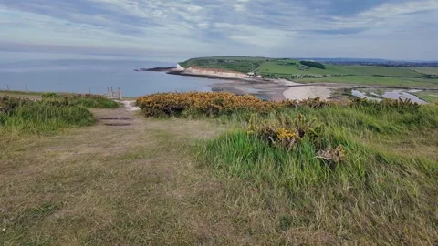 Scenic hilltop path overlooking ocean and coastal cliffs under clear summer sky Stock Footage 309767866