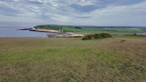 Scenic hilltop path overlooking ocean and coastal cliffs under clear summer sky Stock Footage 309767882