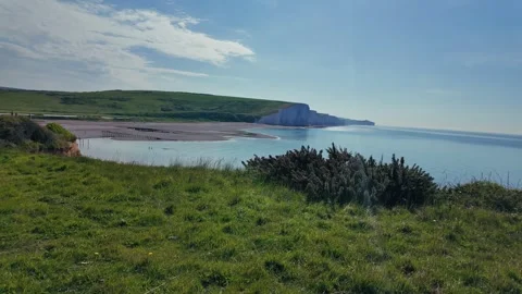 Scenic hilltop path overlooking ocean and coastal cliffs under clear summer sky Stock Footage 309768437