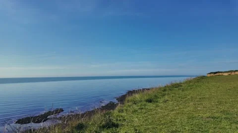 Scenic hilltop path overlooking ocean and coastal cliffs under clear summer sky Stock Footage 309768476