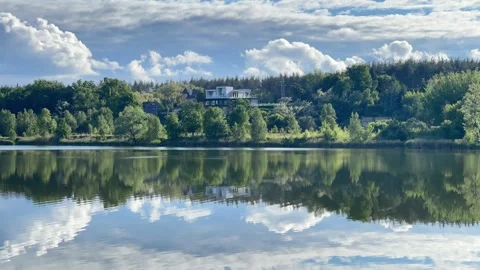 Scenic Lake Reflection with Modern House on Forested Hill Видео 336023738