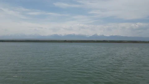 Scenic lake view with snow-capped distant mountains under a cloudy sky. Stock Footage 341275451