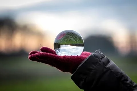 A scenic landscape image reflected inside of a lens ball resting on the red g Stock Photos