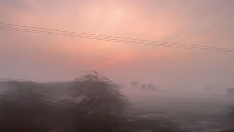 Scenic landscape view from a moving train window during a misty golden hour Stock Footage 333613495