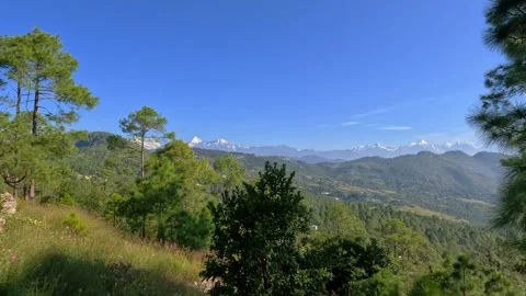 Scenic mountain landscape featuring distant snow peaks and pine trees under.. Video stock 338285238