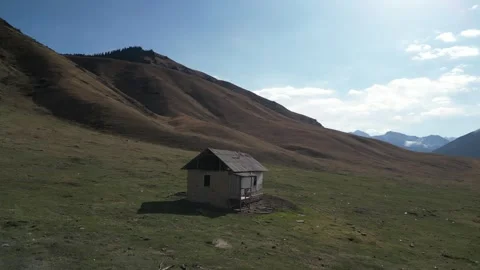 Scenic mountain landscape with rustic cabin, camera pans rightward Stock Footage 320396824