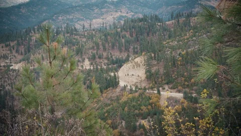 Scenic Mountain Range With Multi-colored Trees and Car Driving Down a Dirt Road Stock Footage 90870170