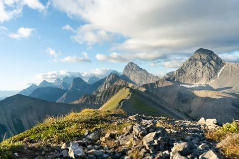 Scenic mountain range with peaks and valleys under a partly cloudy sky. Stock Photos