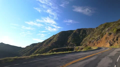 The Scenic Mountain Road Meanders Gracefully Beneath the Bright Glare of the Stock Footage 308359585