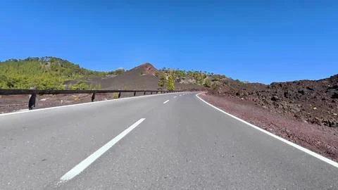 A Scenic Mountain Road, Surrounded by Dramatic Volcanic Terrain and a Bright Stock Photos
