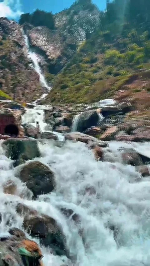 Scenic mountain waterfall flowing over rocky boulders into a fast river stream Video stock 344325319