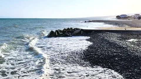 Scenic Pebble Beach with Gentle Waves Crashing on the Shore and Coastal Hous Stock Footage 332252736