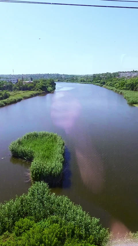Scenic point of view look through a passenger train window at a wide river with Stock Footage 338398220