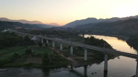 Scenic Railway Bridge Over River and Mountains at Sunset in Rural Landscape Stock Footage 343919059