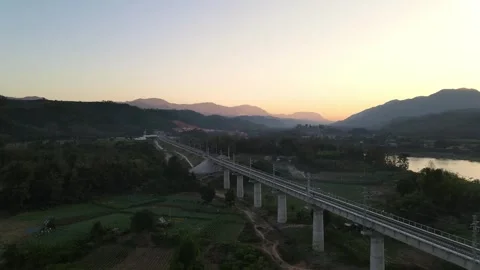 Scenic Railway Bridge Over River and Mountains at Sunset in Rural Landscape Stock Footage 343919095