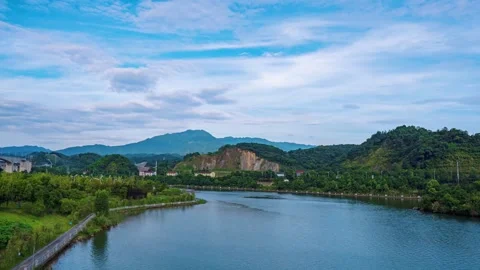 Scenic river flowing through lush green mountains under a bright blue cloudy sky Video stock 341956724