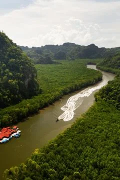 Scenic river flows smoothly through dense greenery, with several boats moving Stock-Fotos