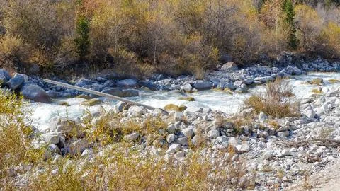 Scenic river flows through rocky landscape with autumn foliage, showcasing Stock Photos