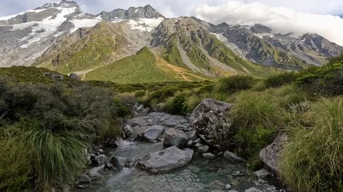 A scenic river with rugged mountains in the background along the Hooker Valley Stock Footage 318203872