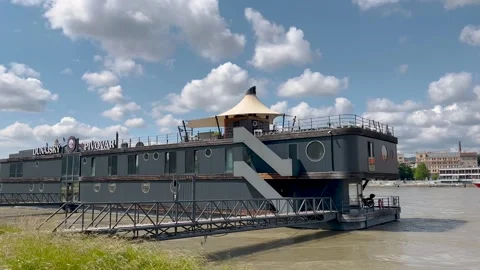 A scenic river view with a docked black boat in the foreground Stock-Footage 301279262